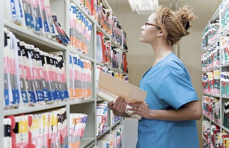 medical billing professional standing next to filing cabinet